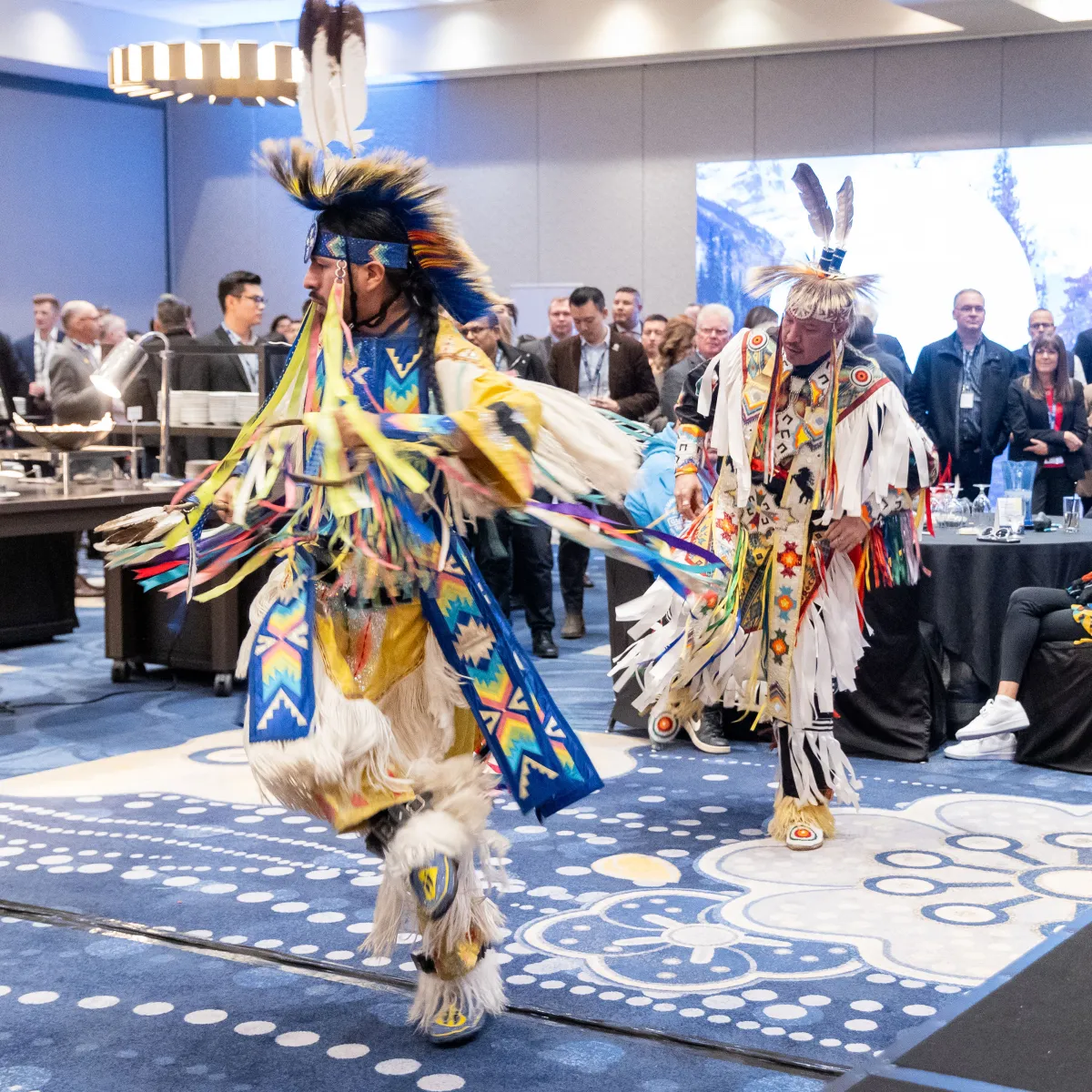 Two dancers in traditional attire doing ceremonial dance at AIOC Enoch office opening