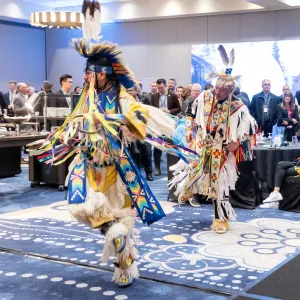 Two dancers in traditional attire doing ceremonial dance at AIOC Enoch office opening