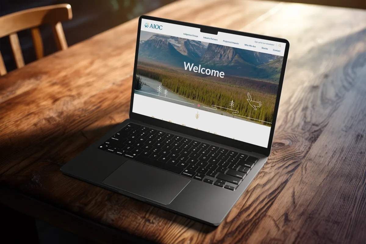 Open laptop on wood grain table showing the AIOC website
